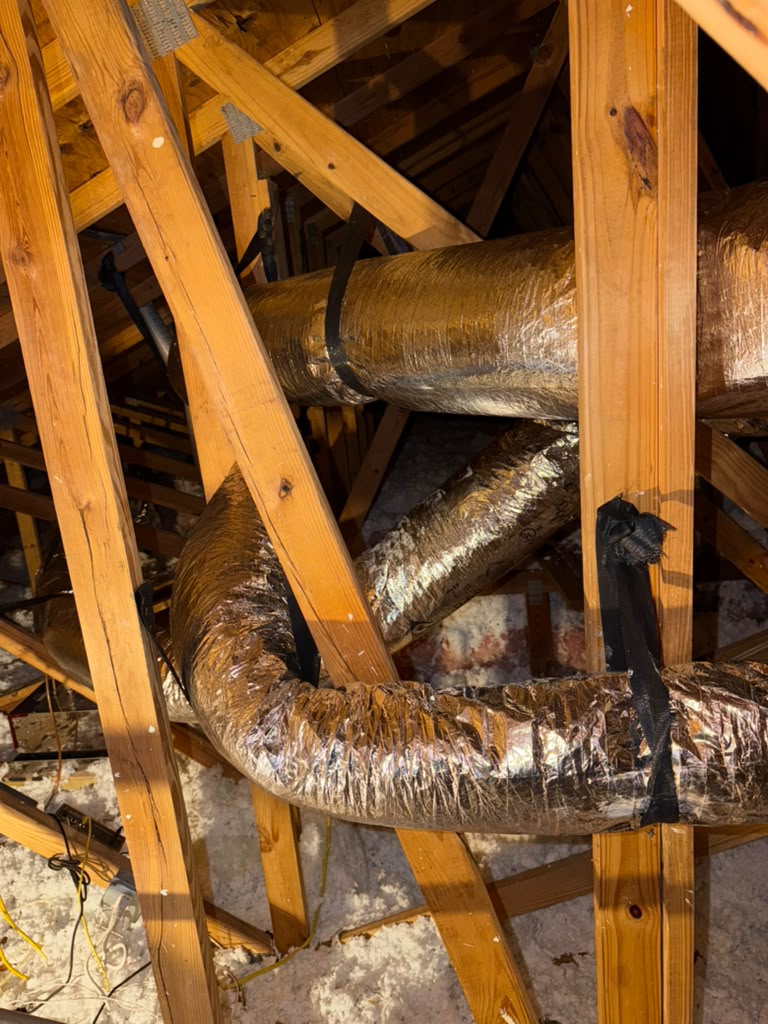 Insulated attic ducts hanging from the roof framing